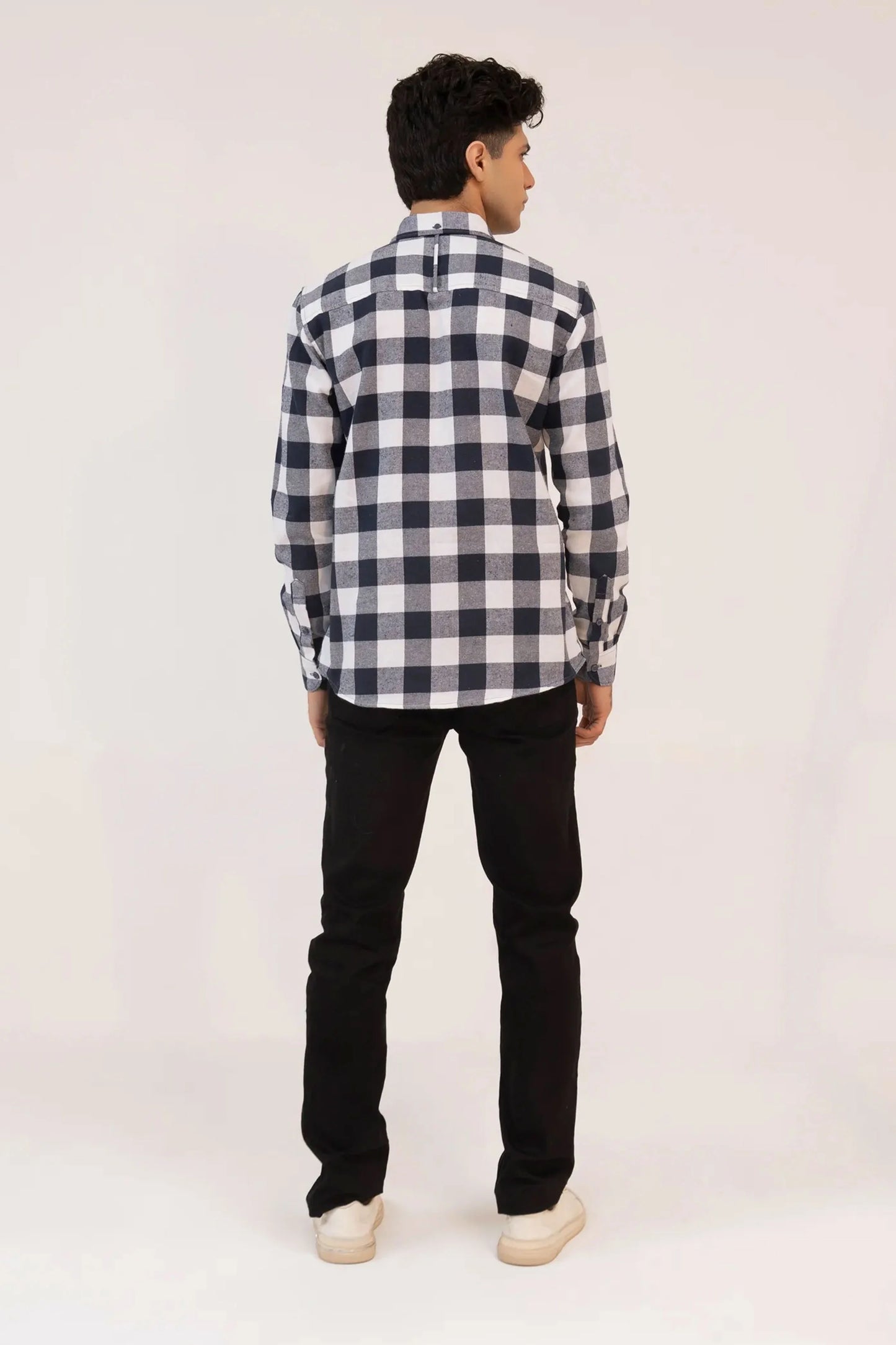 A back view of a man dressed in a checkered shirt and black jeans