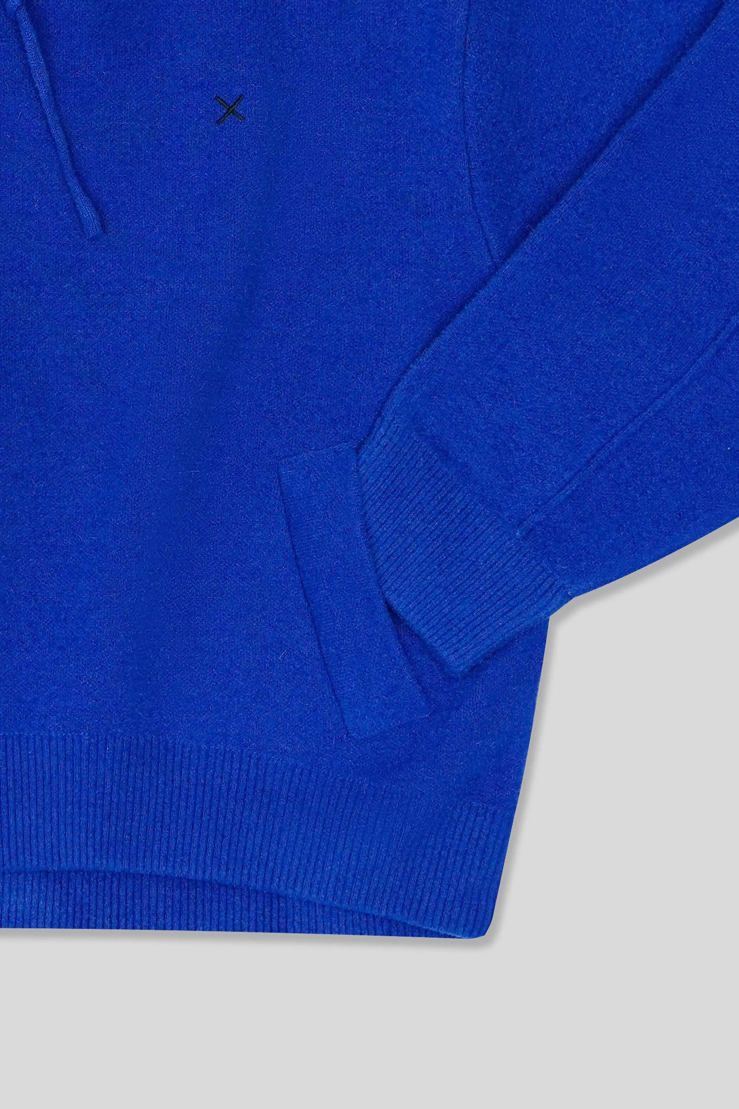 Blue sweater with a small black logo on a light gray background