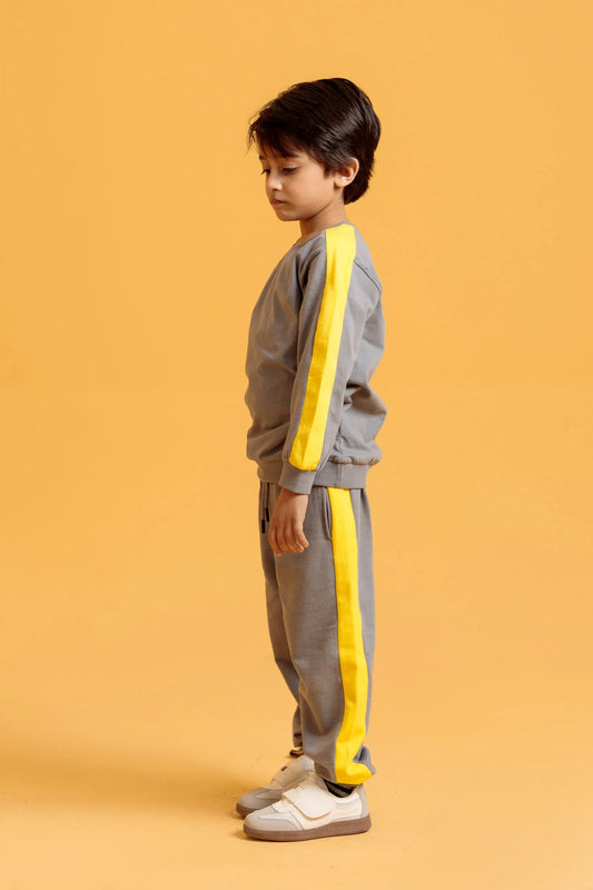 Child wearing a gray and yellow tracksuit on an orange background