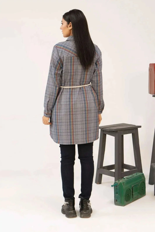 Girl wearing a plaid coat standing next to a stool and a green radio