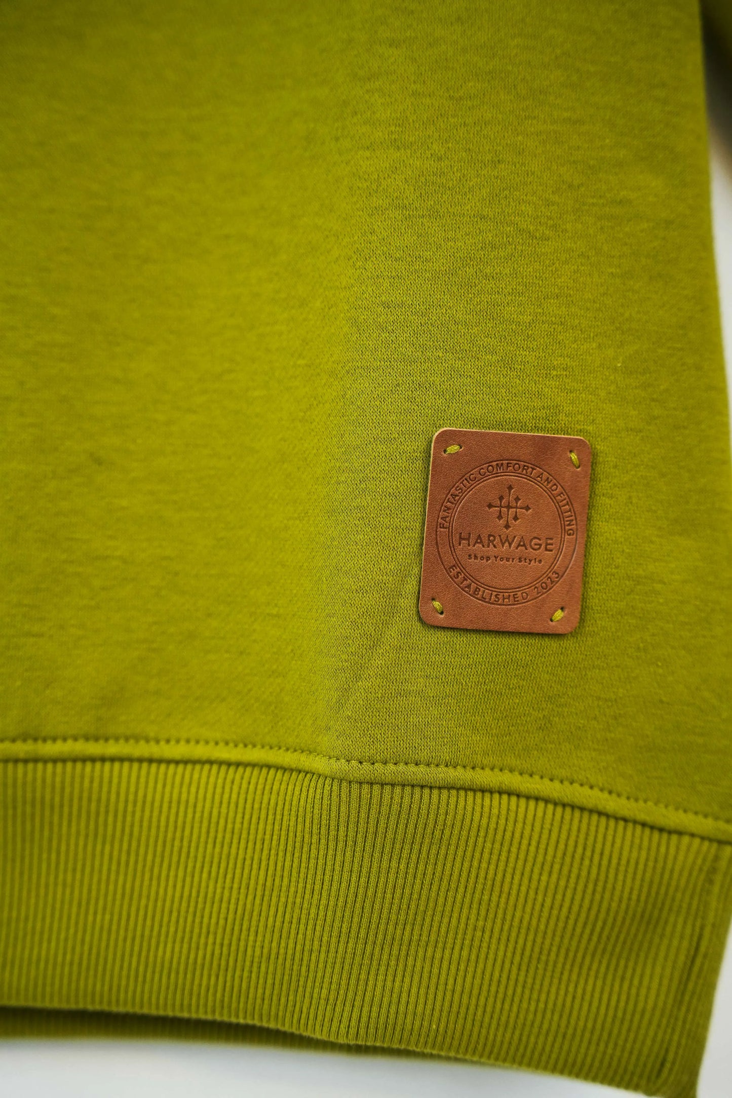 Lower hem detail with leather tag on olive green fabric