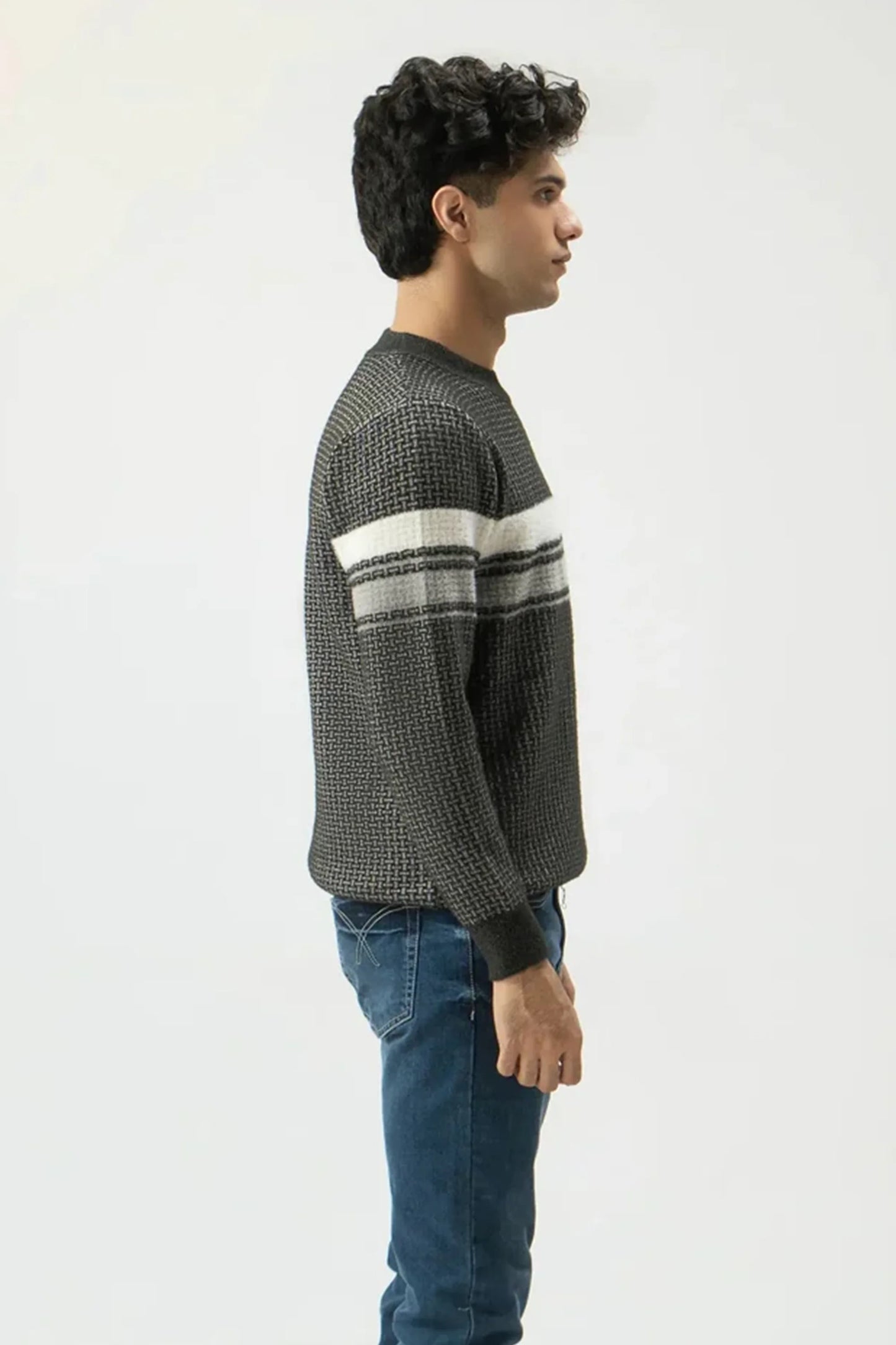 Man wearing a patterned sweater and jeans on a white background