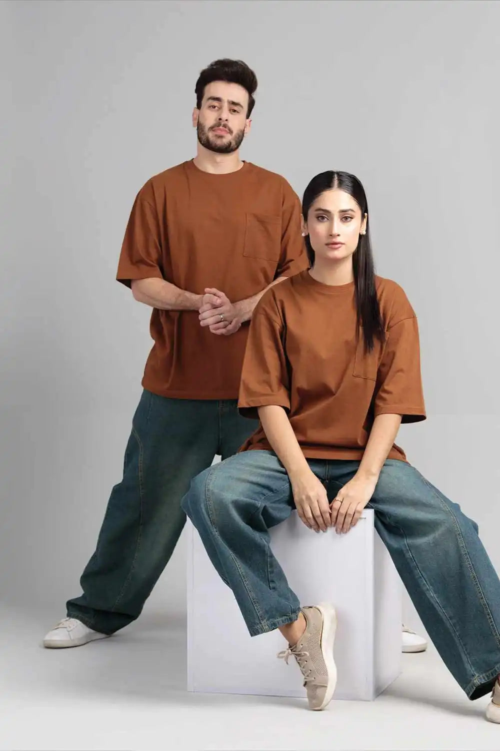 A man and woman wearing matching brown t-shirts and jeans