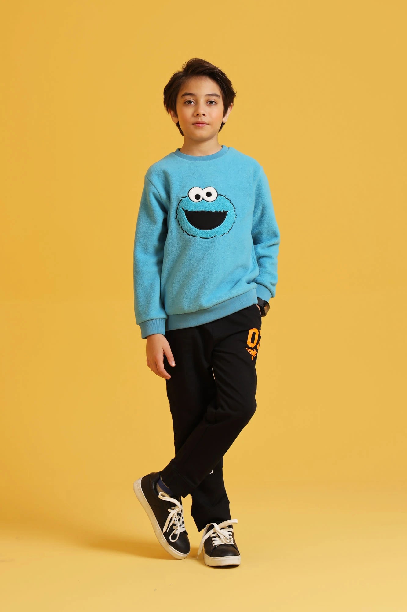Young boy styling a blue sweatshirt with black trousers