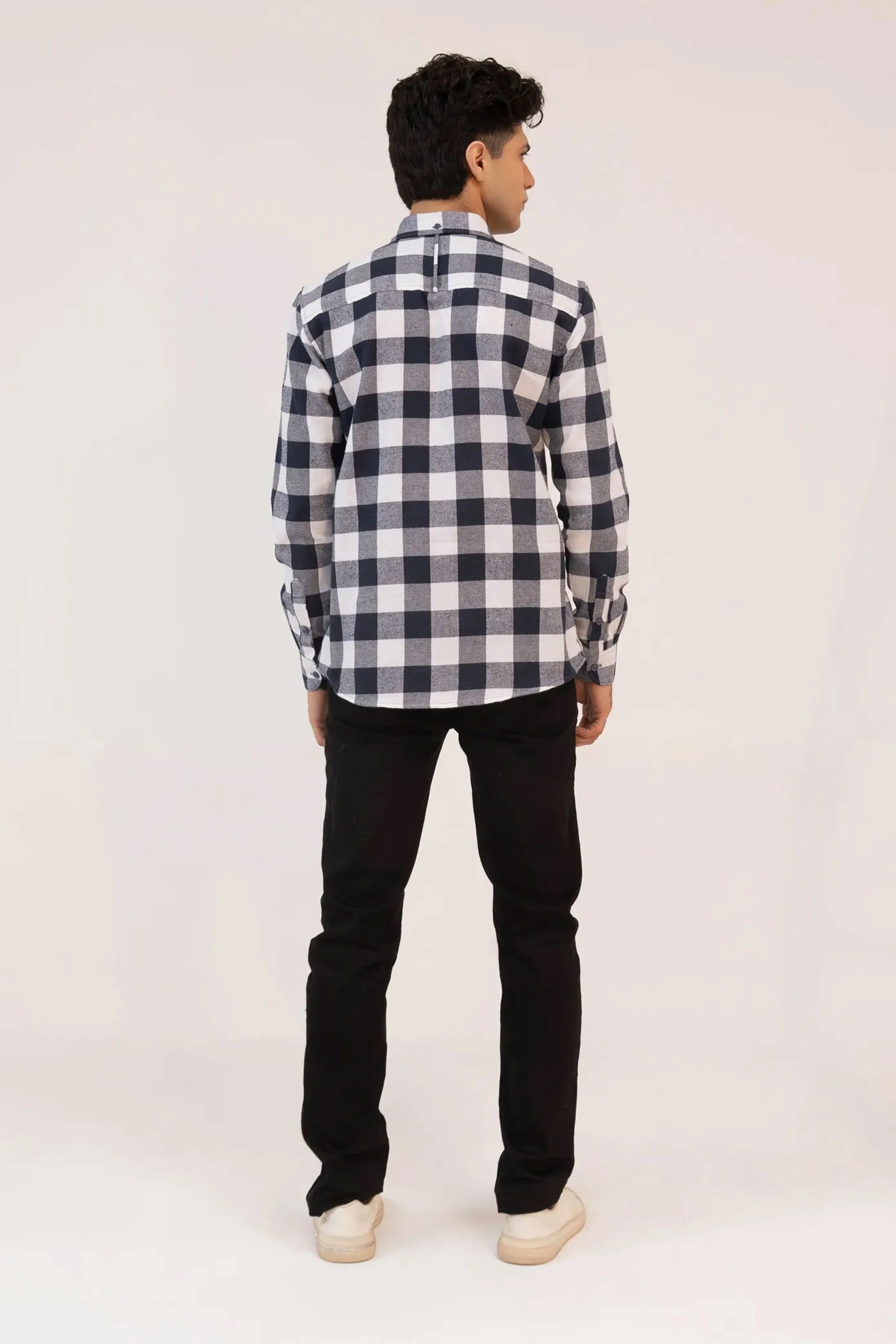 A back view of a man dressed in a checkered shirt and black jeans