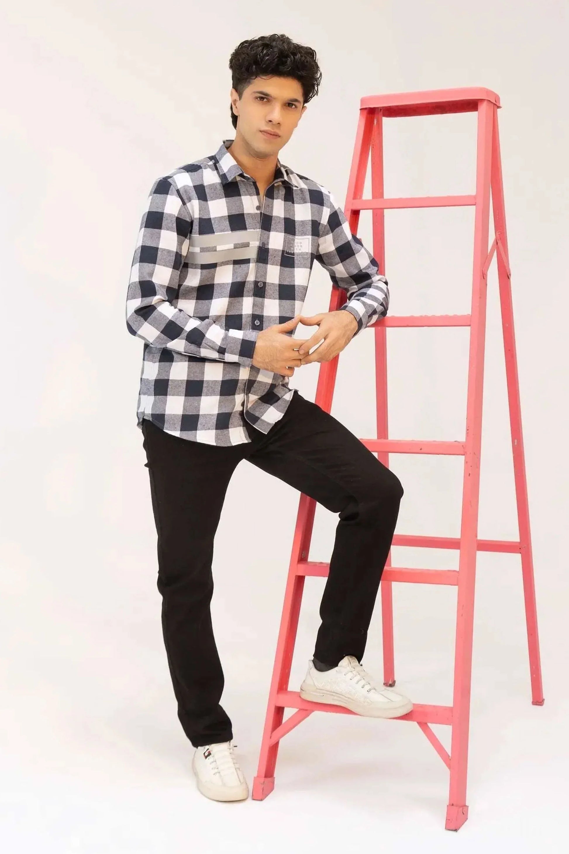 A man dressed in a black and white checkered shirt and black jeans