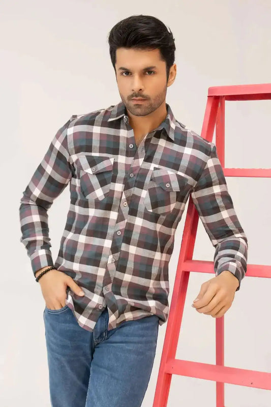 A man wearing a plaid shirt and jeans standing next to a red ladder