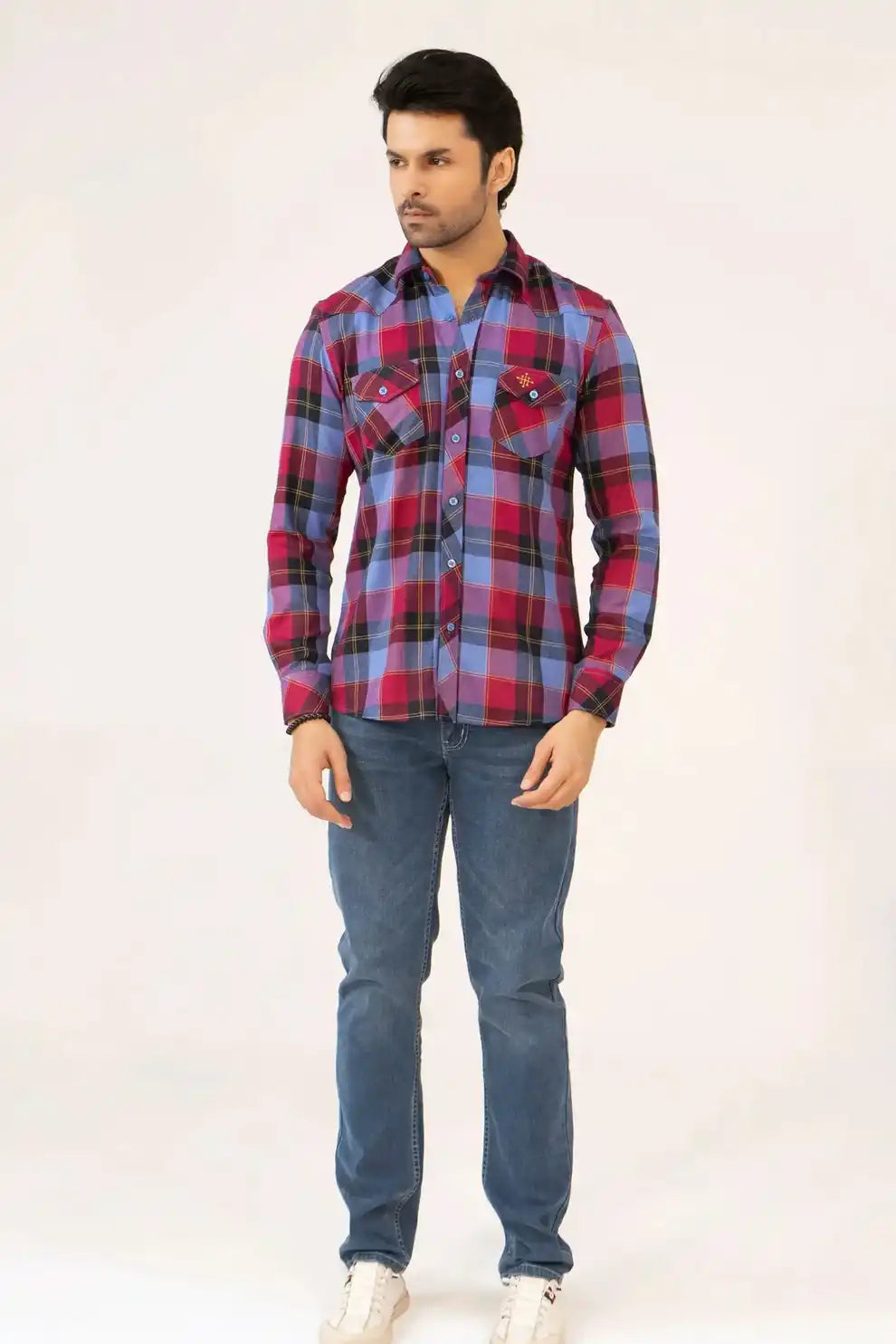 A man wearing a red and blue plaid shirt with jeans