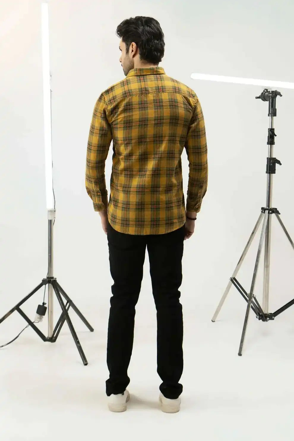 A man wearing a yellow plaid shirt and black pants