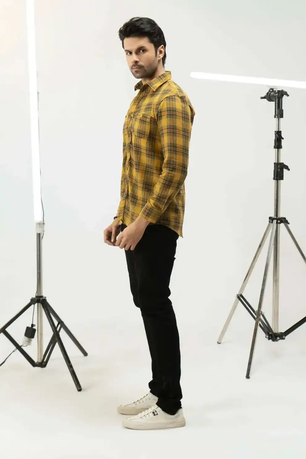 A man wearing a yellow plaid shirt with black pants