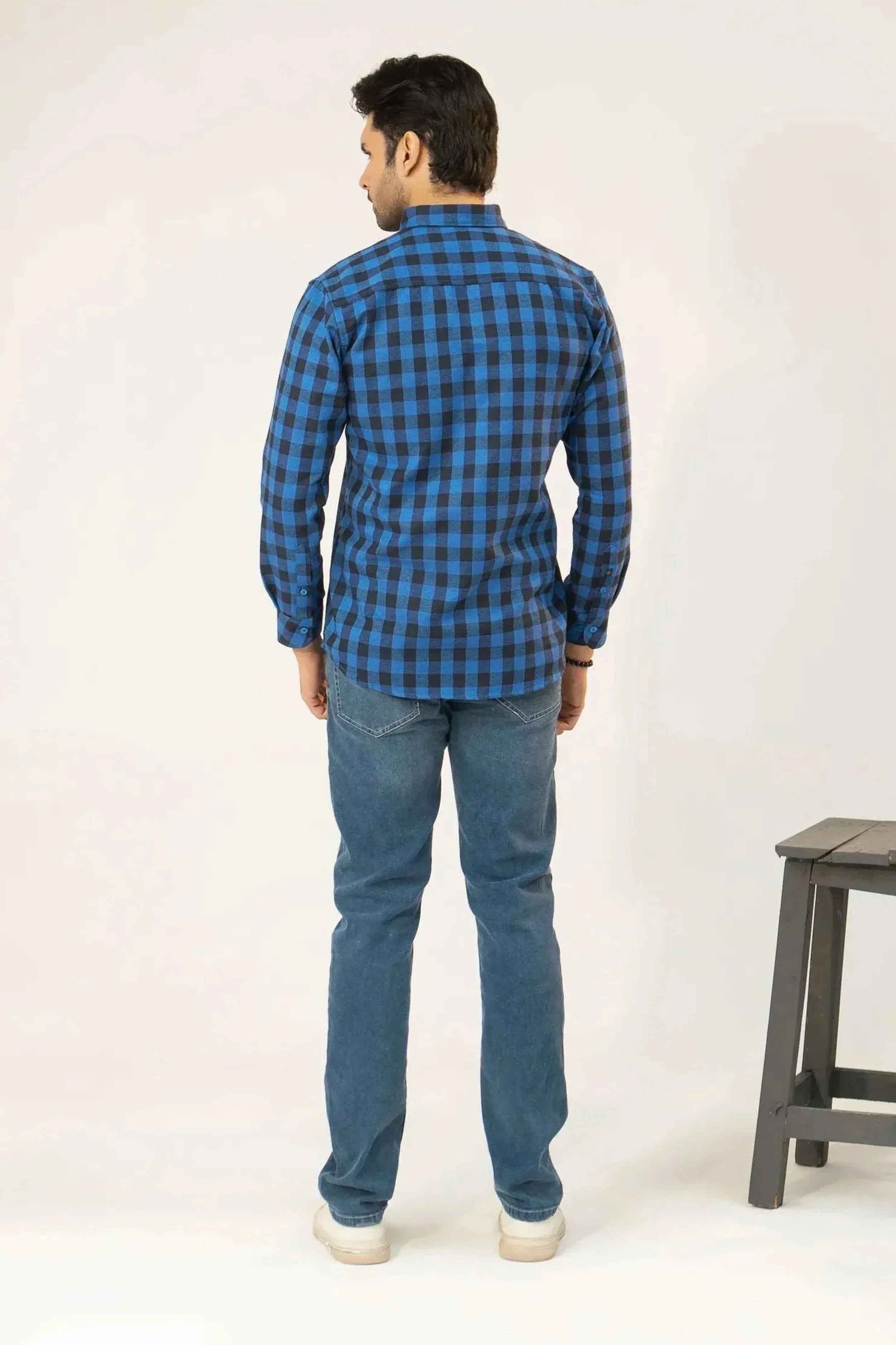 Back view of a man in a blue checkered shirt and blue jeans