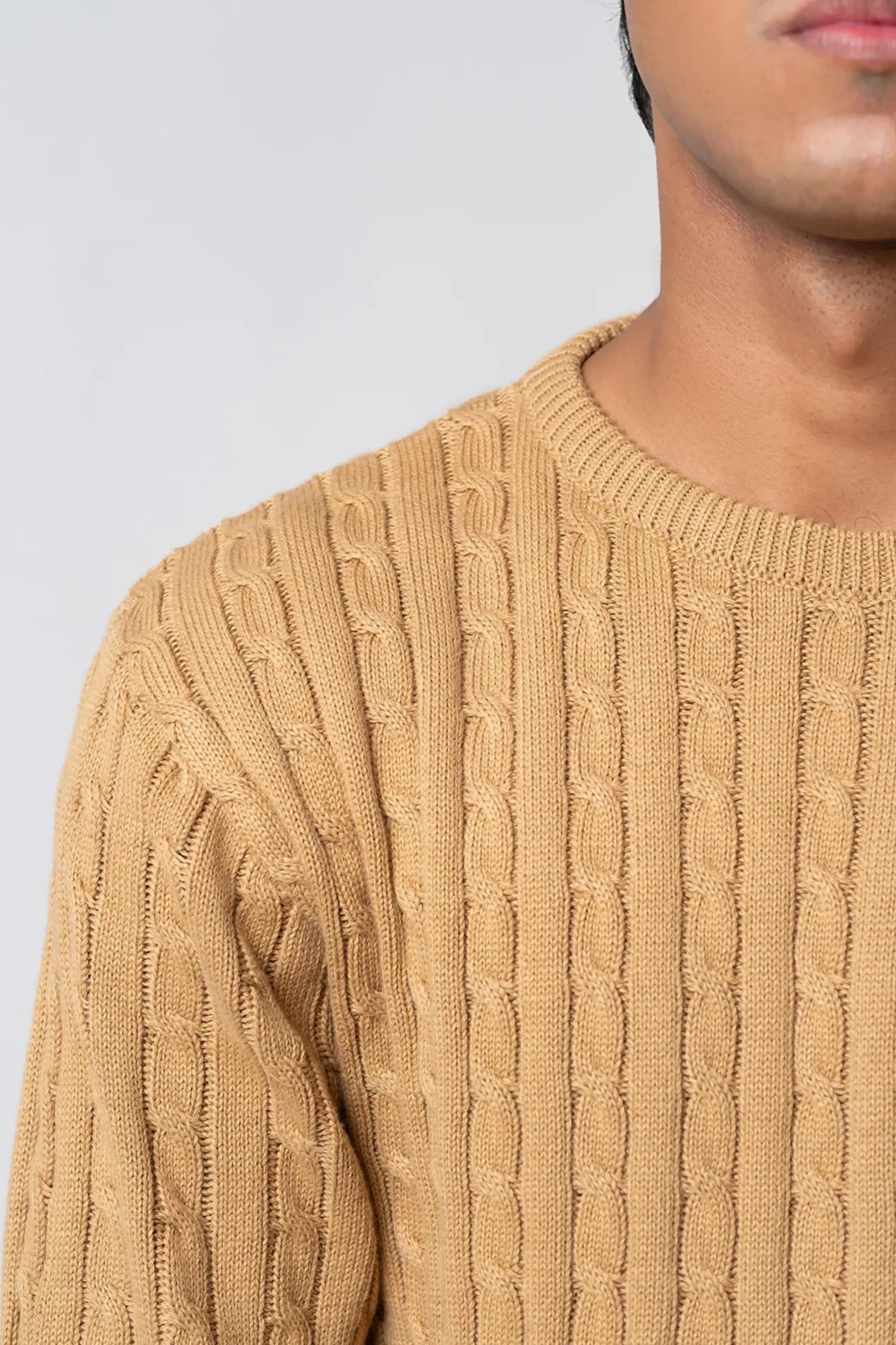 Close-up of beige crew neck cable knit sweater texture