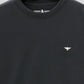 Black t-shirt with a small logo on a light gray background