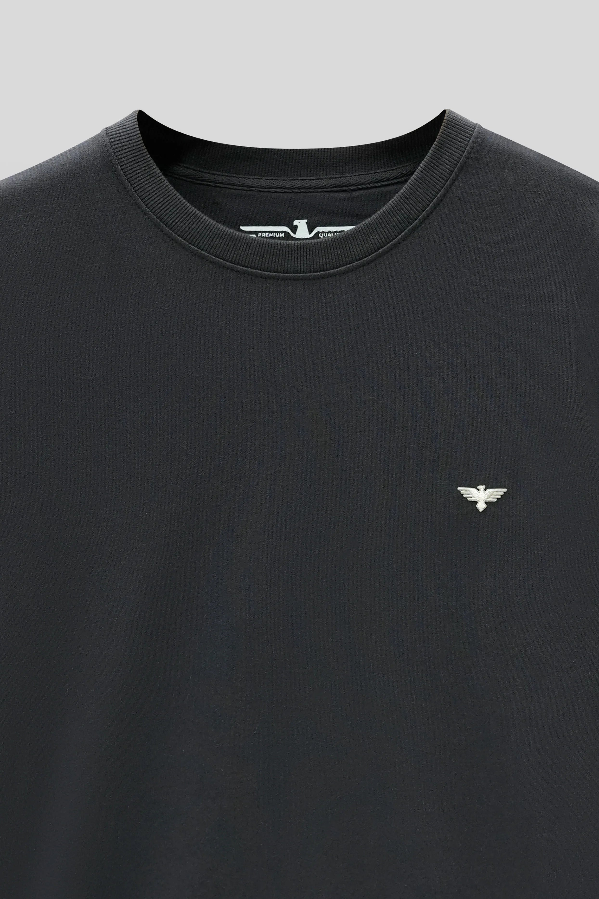 Black t-shirt with a small logo on a light gray background