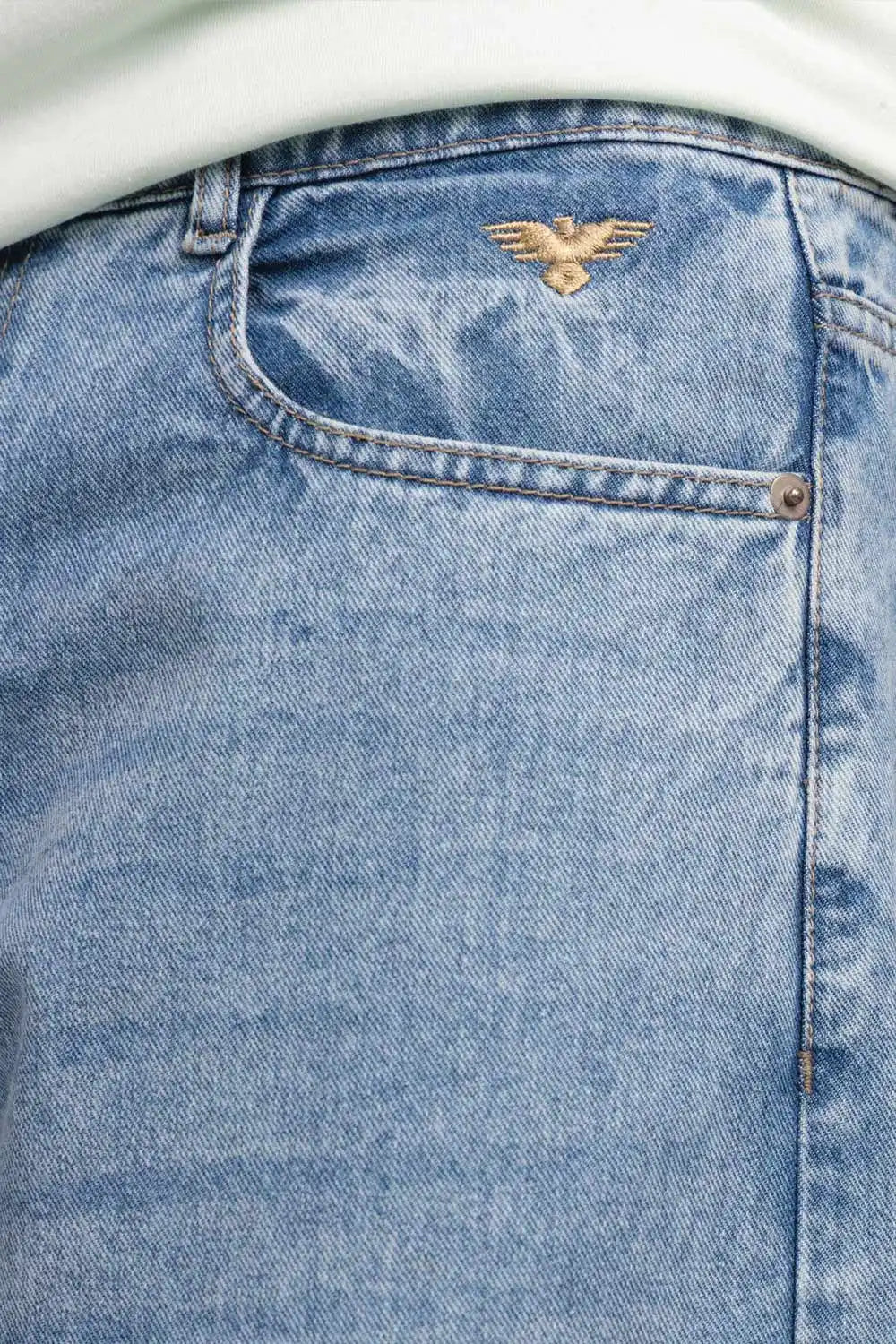 Close-up of blue denim jeans with an eagle logo on the pocket