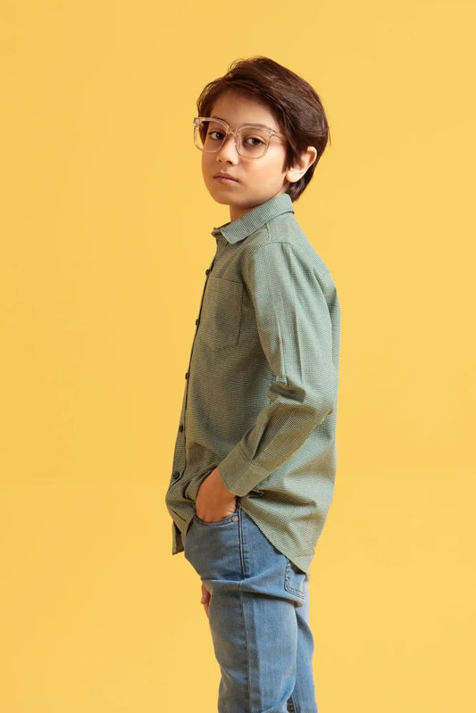 Boy wearing a green shirt and blue jeans against a yellow background
