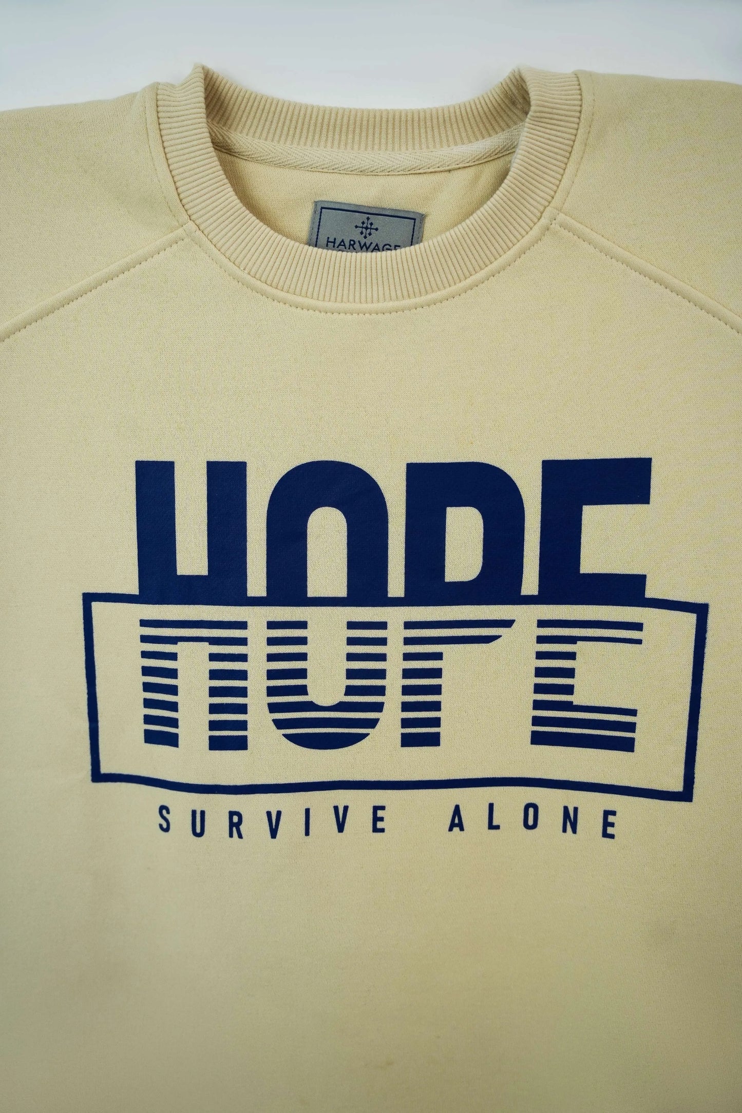 Chest-level detail showing slogan print on a cream sweatshirt