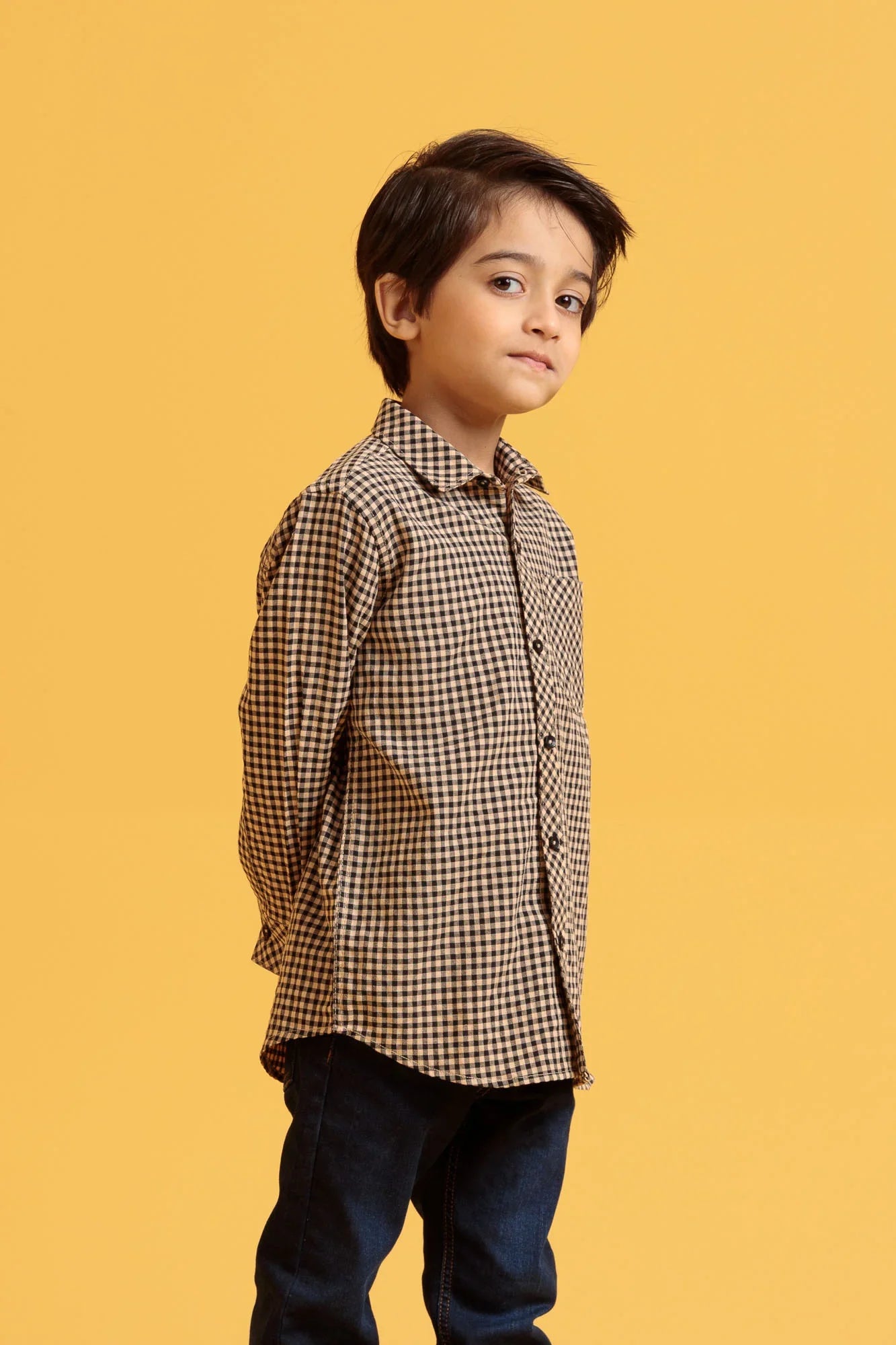 Child wearing a checkered shirt against a yellow background