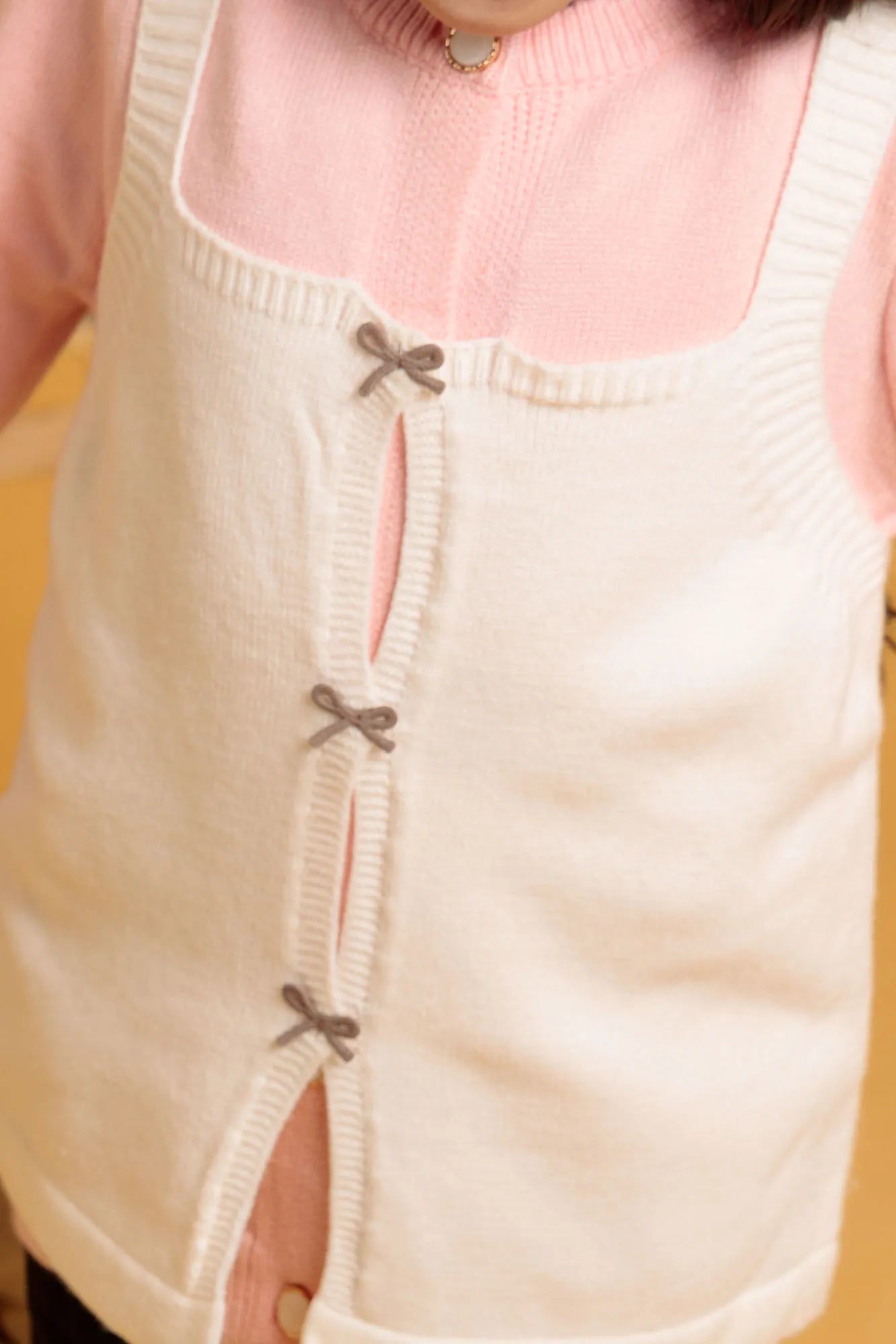Close-up of a beige apron with decorative buttons on a pink shirt
