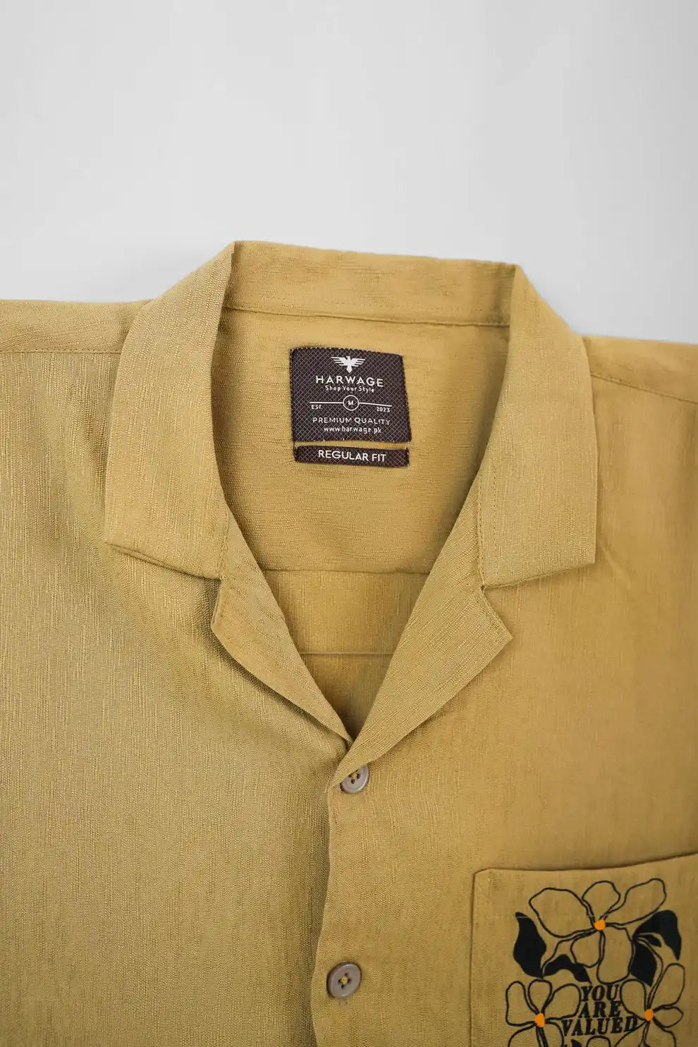 Close-up of a beige shirt with a collar and a label