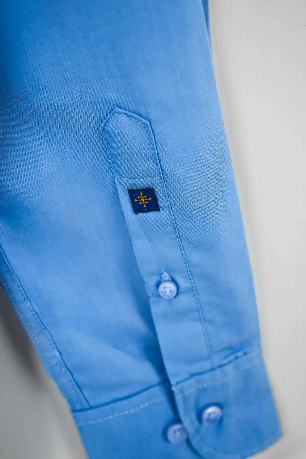 Close-up of a blue shirt sleeve with a brand logo