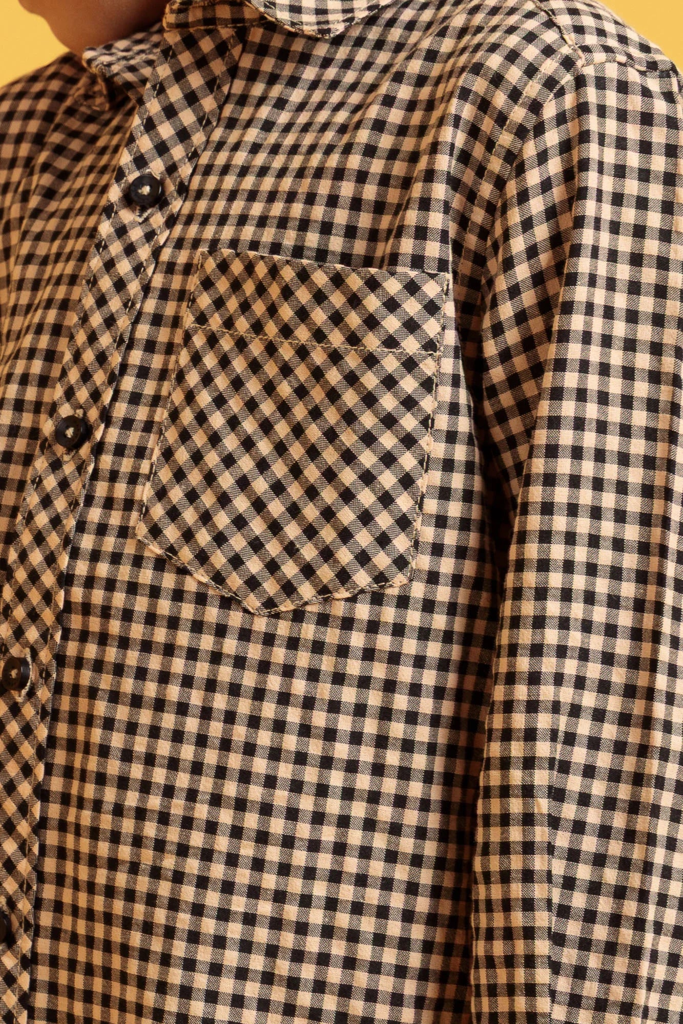 Close-up of a checkered shirt with a pocket on a yellow background