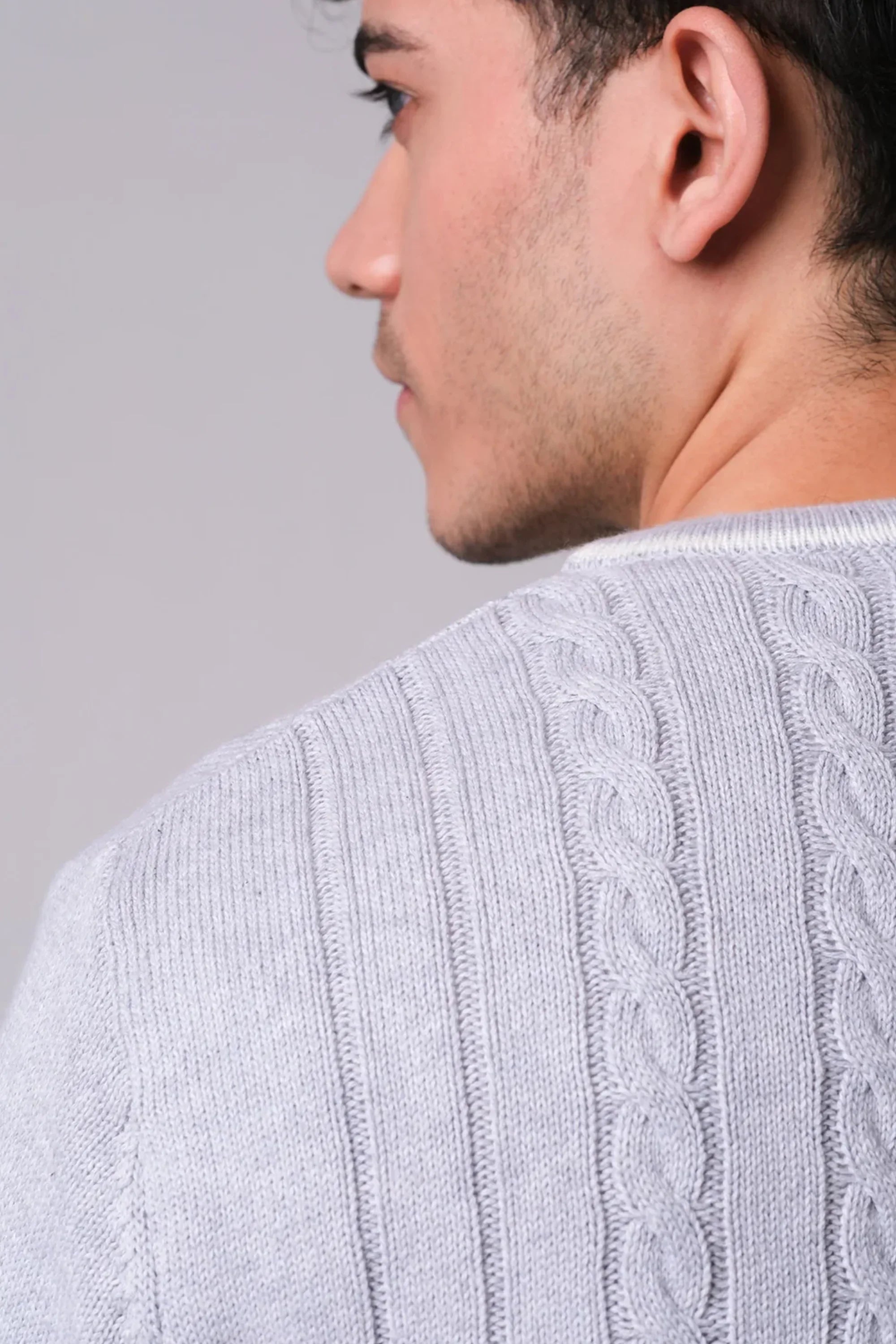 Close-up of a person wearing a light gray cable knit sweater