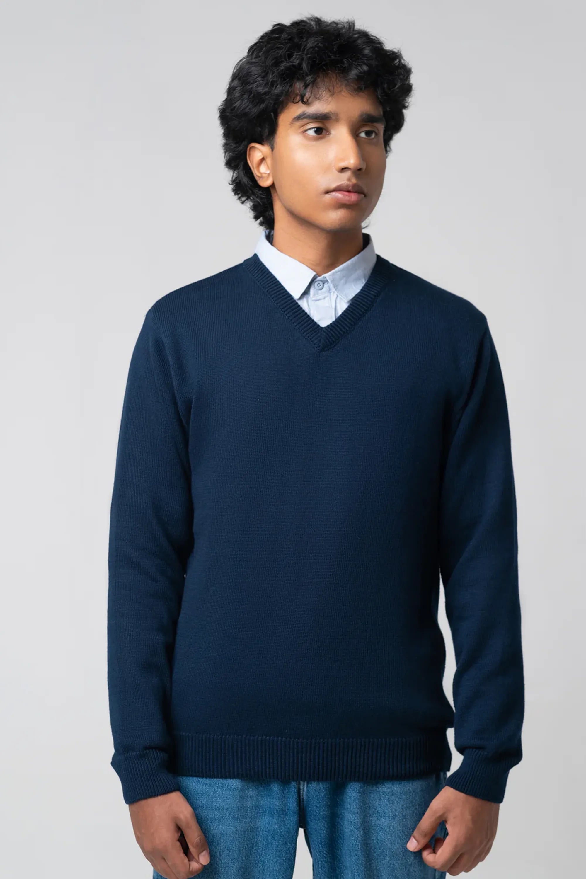 Front-facing pose wearing men's v neck cardigan navy with jeans