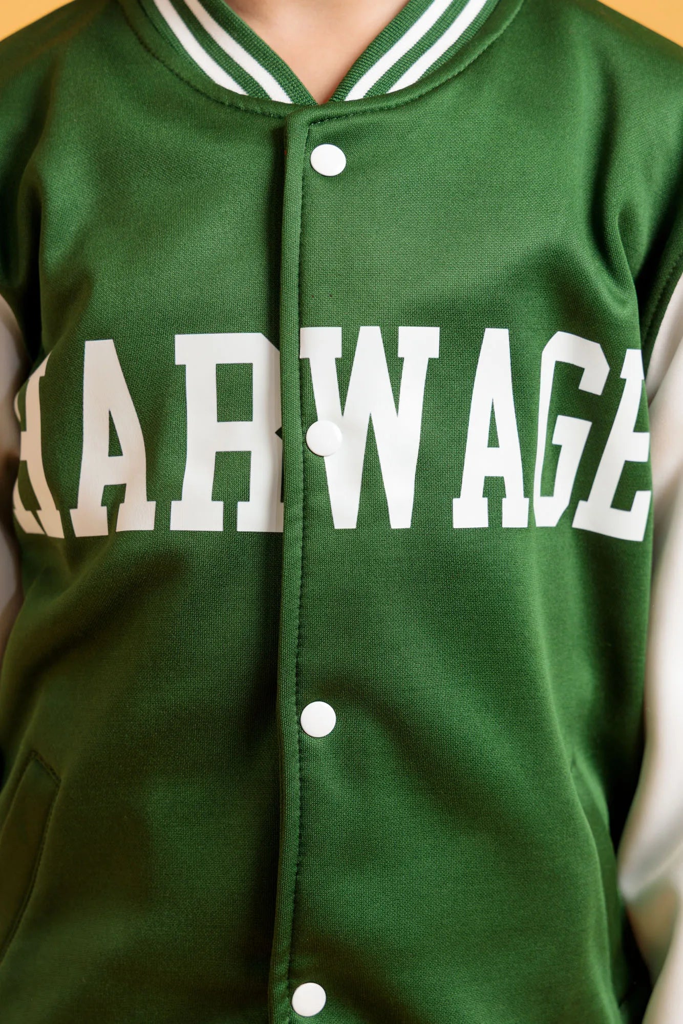 Front close up of green varsity jacket with button closure and logo