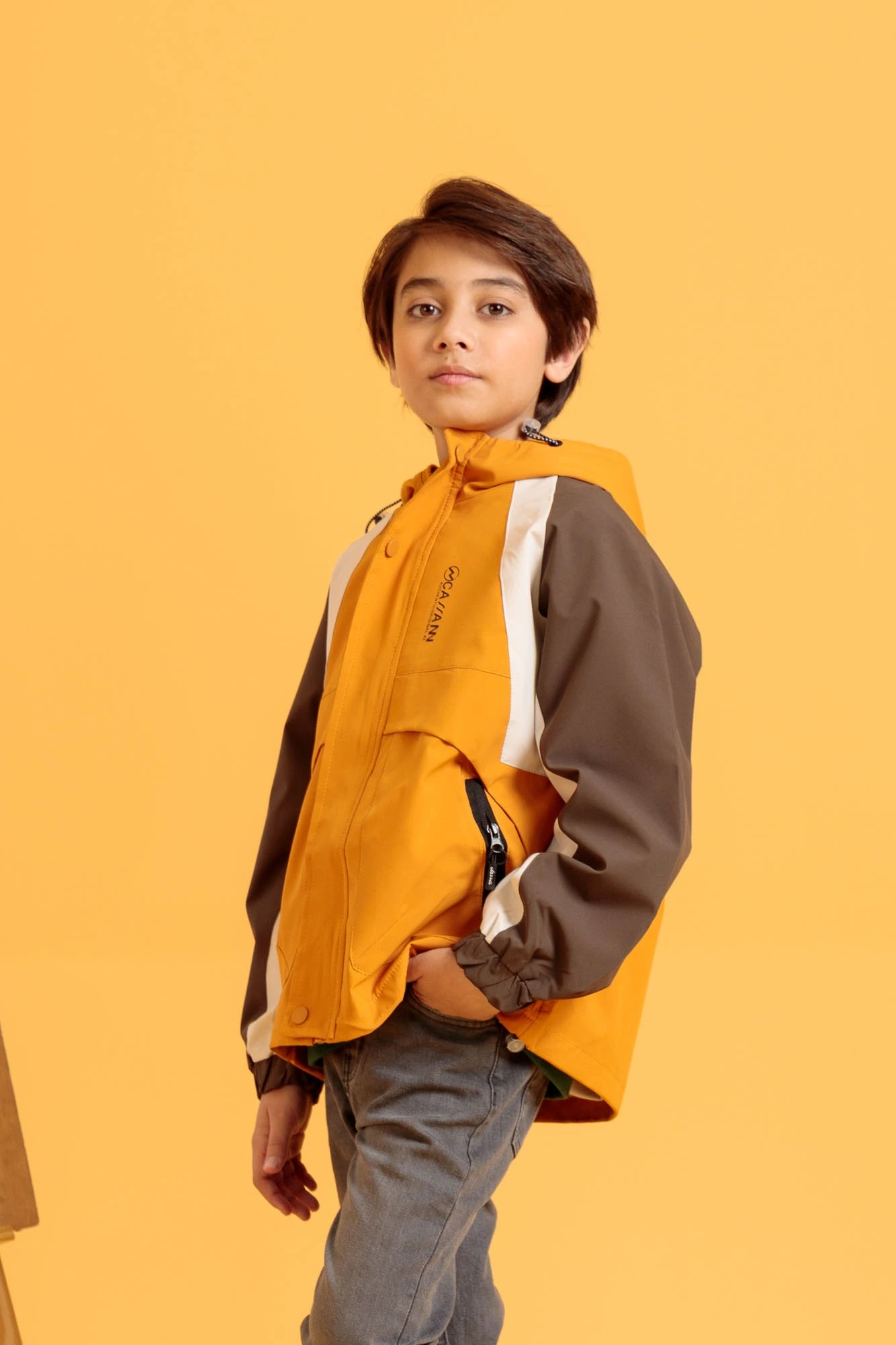 Full body studio image of junior boy in harvest gold jacket