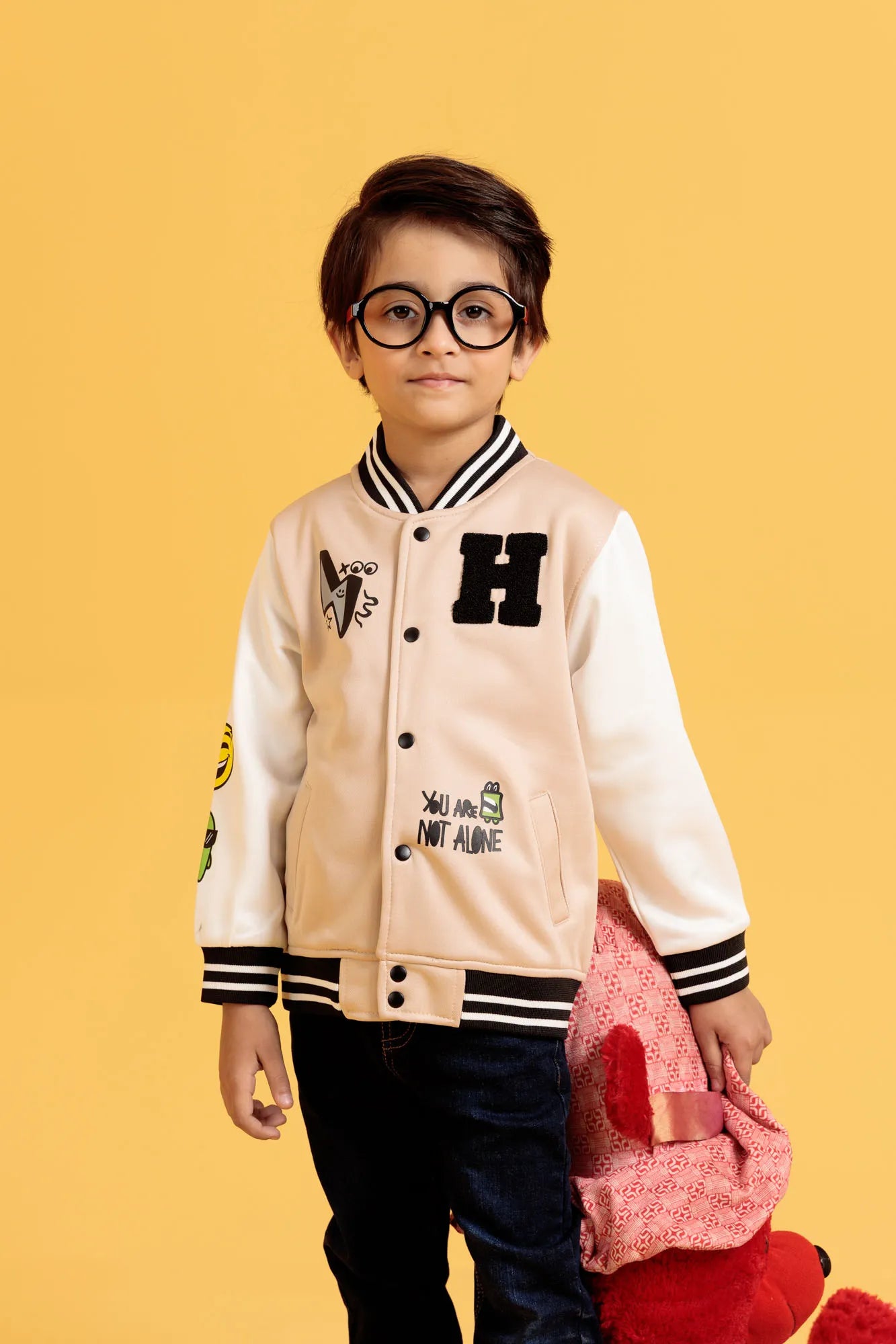 Full body view of boy in turtledove baseball jacket and jeans