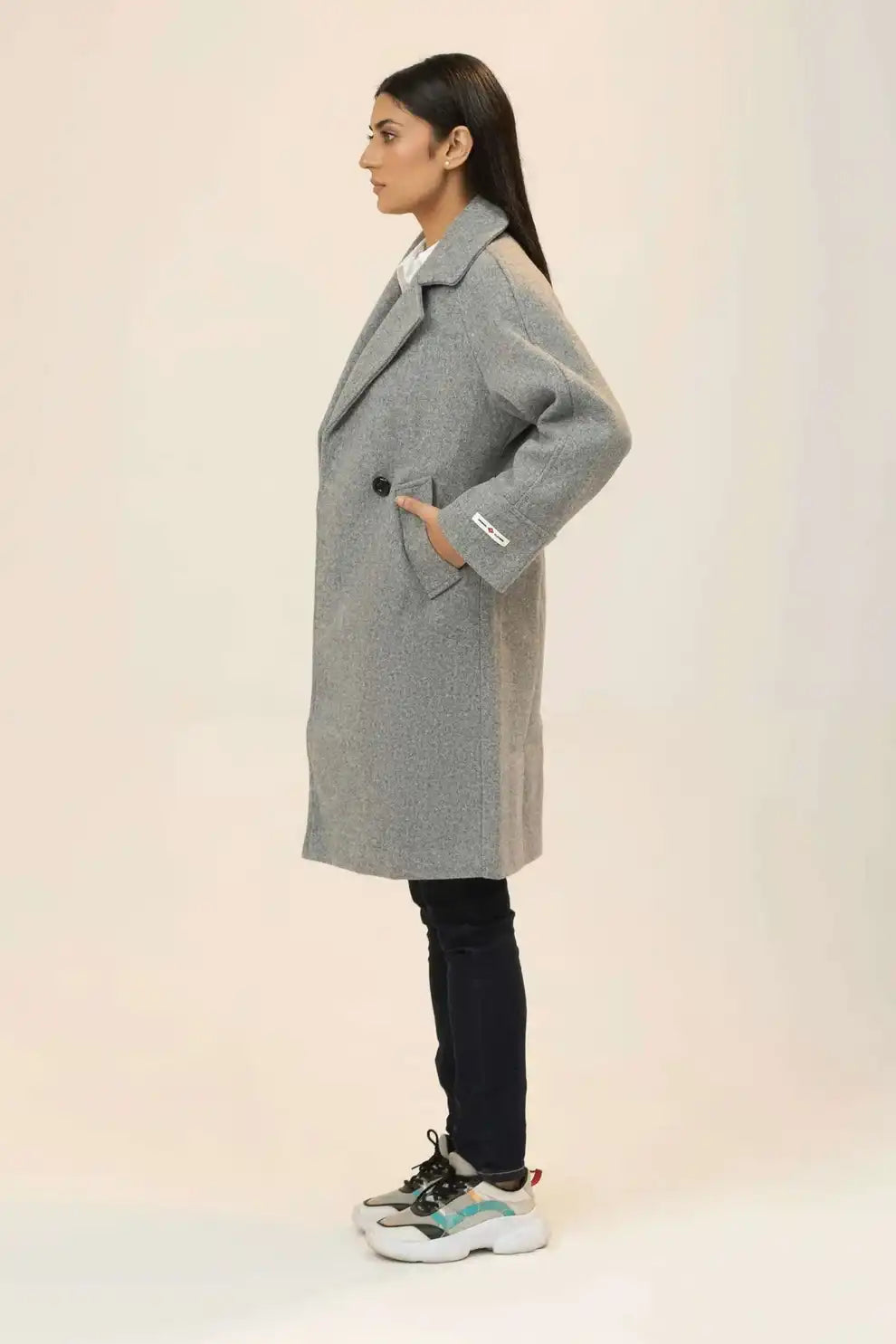 Girl wearing a gray coat on a plain background