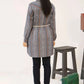Girl wearing a plaid coat standing next to a stool and a green radio