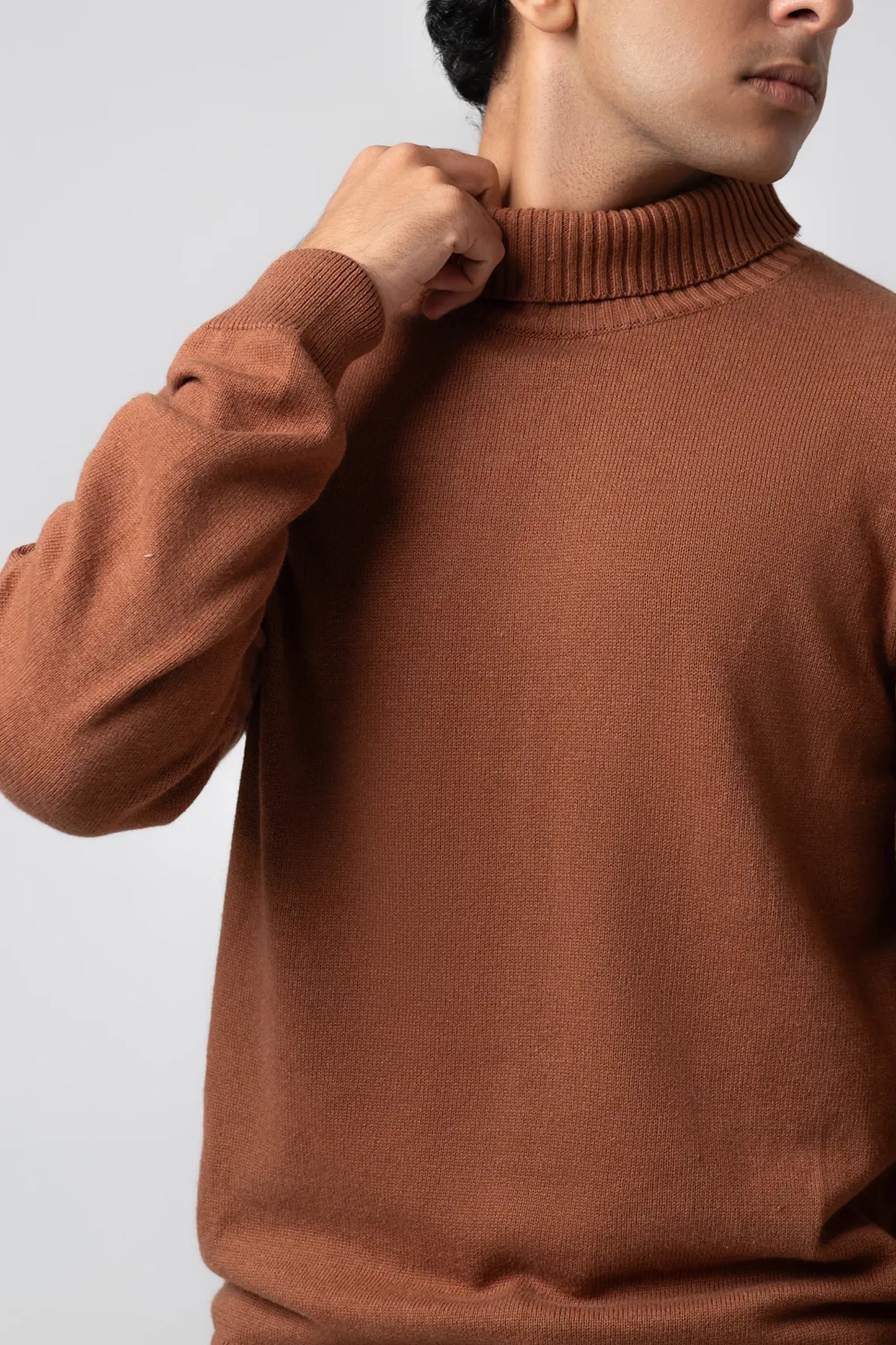 Hand-to-collar close-up showing ribbed neck on brown sweater