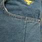 Close-up of blue denim jeans with a gold eagle logo on the pocket