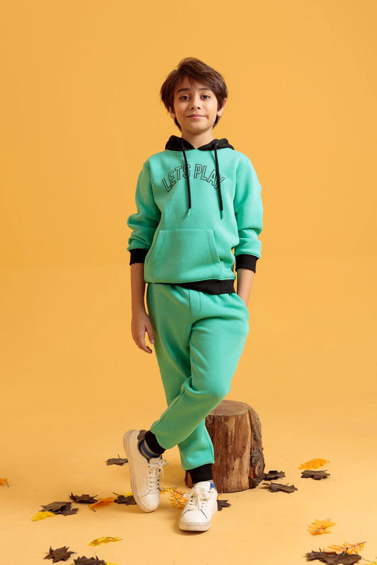 Junior Boys’ Aqua Green Two-Piece Outfit with leaves on the ground.