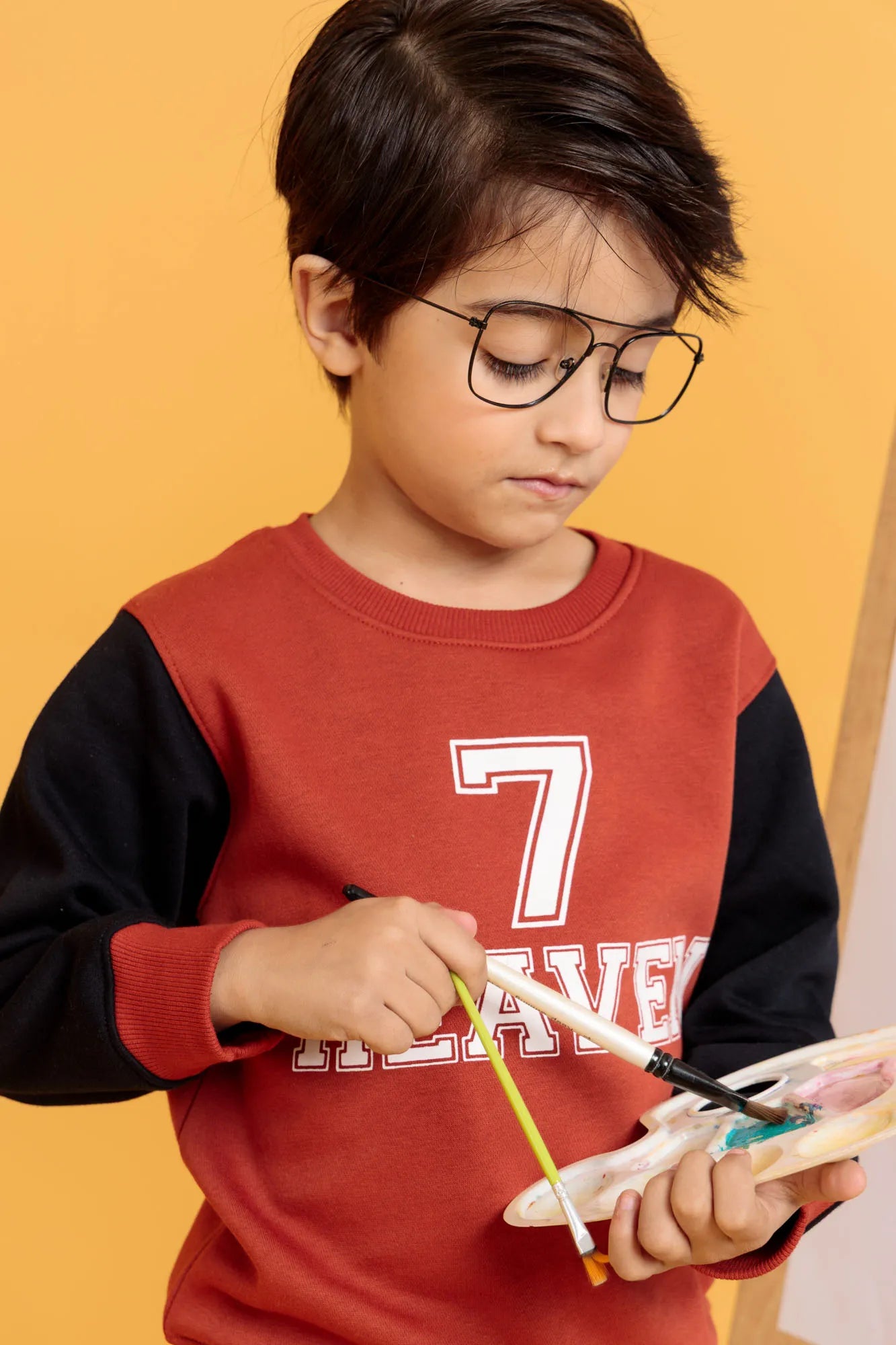 Little boy in glasses wearing orange rust sweatshirt