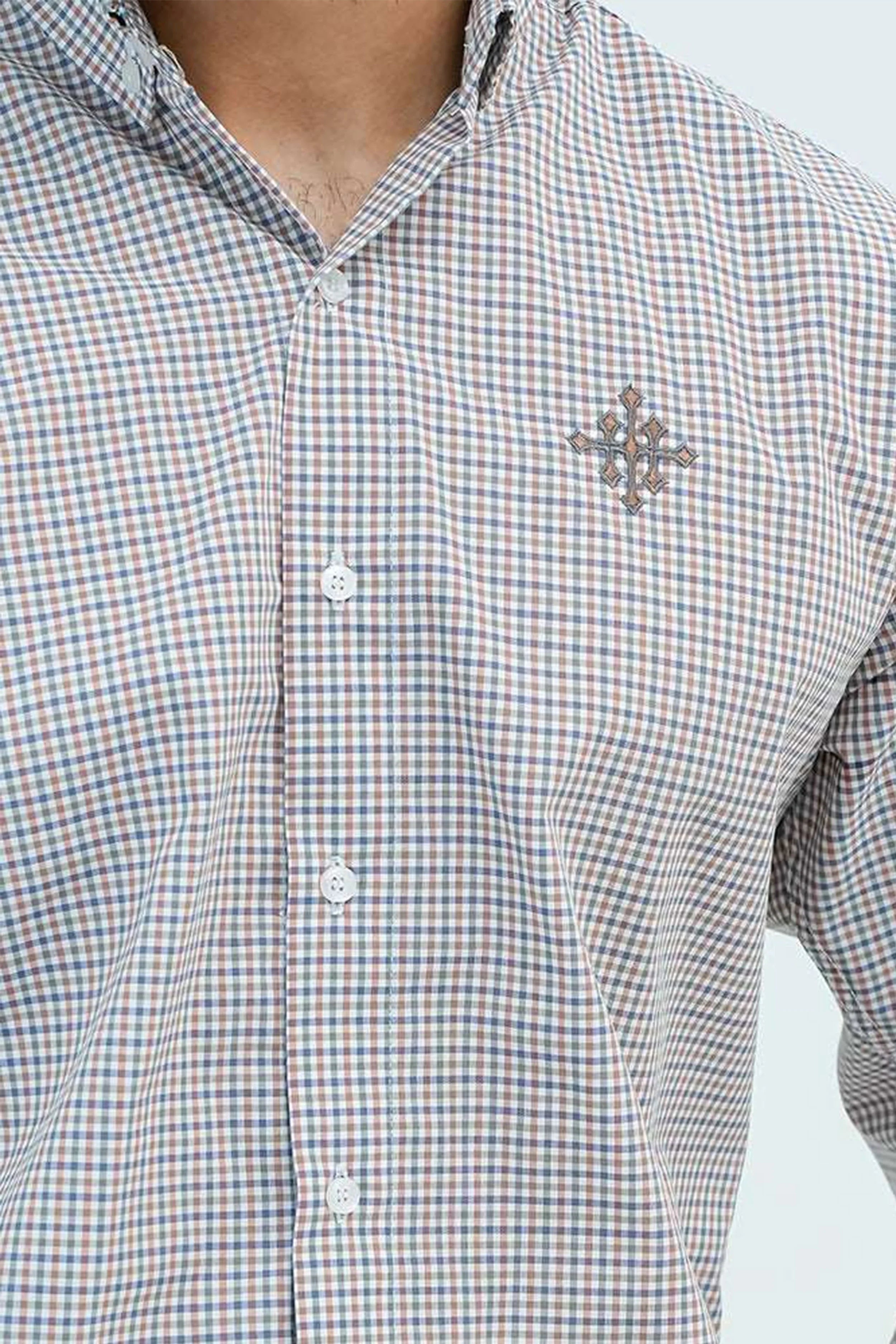 Close-up logo detail on checkered brown casual shirt