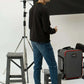 Man standing in a photography studio with equipment and a black backdrop