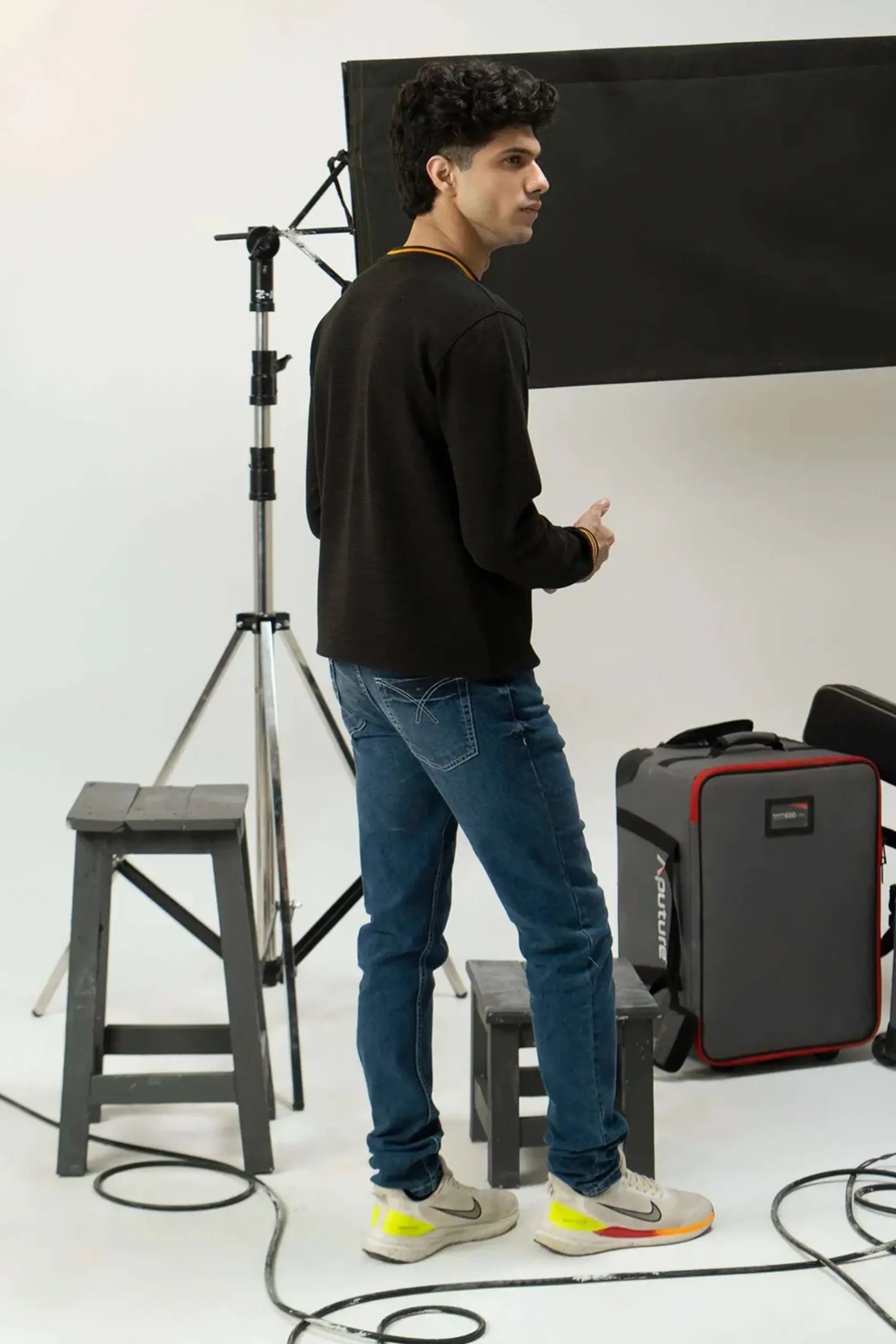 Man standing in a photography studio with equipment and a black backdrop