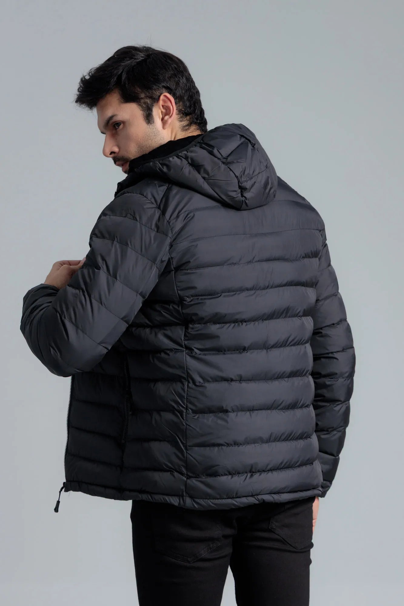 Man wearing a black puffer jacket against a gray background