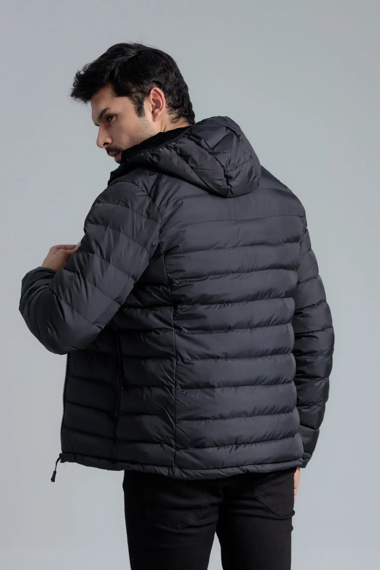 Man wearing a black puffer jacket against a gray background