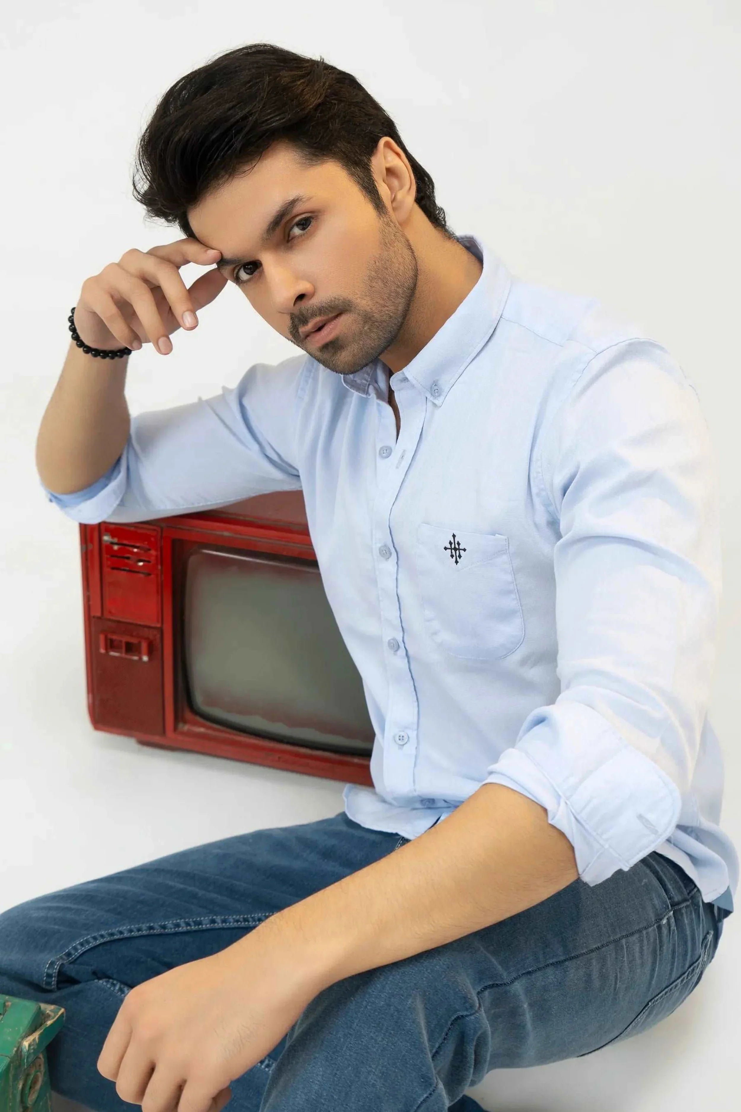 Man wearing a clear sky shirt with a vintage red television set 