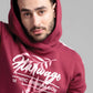 Man wearing a maroon hoodie with white text and design on a gray background