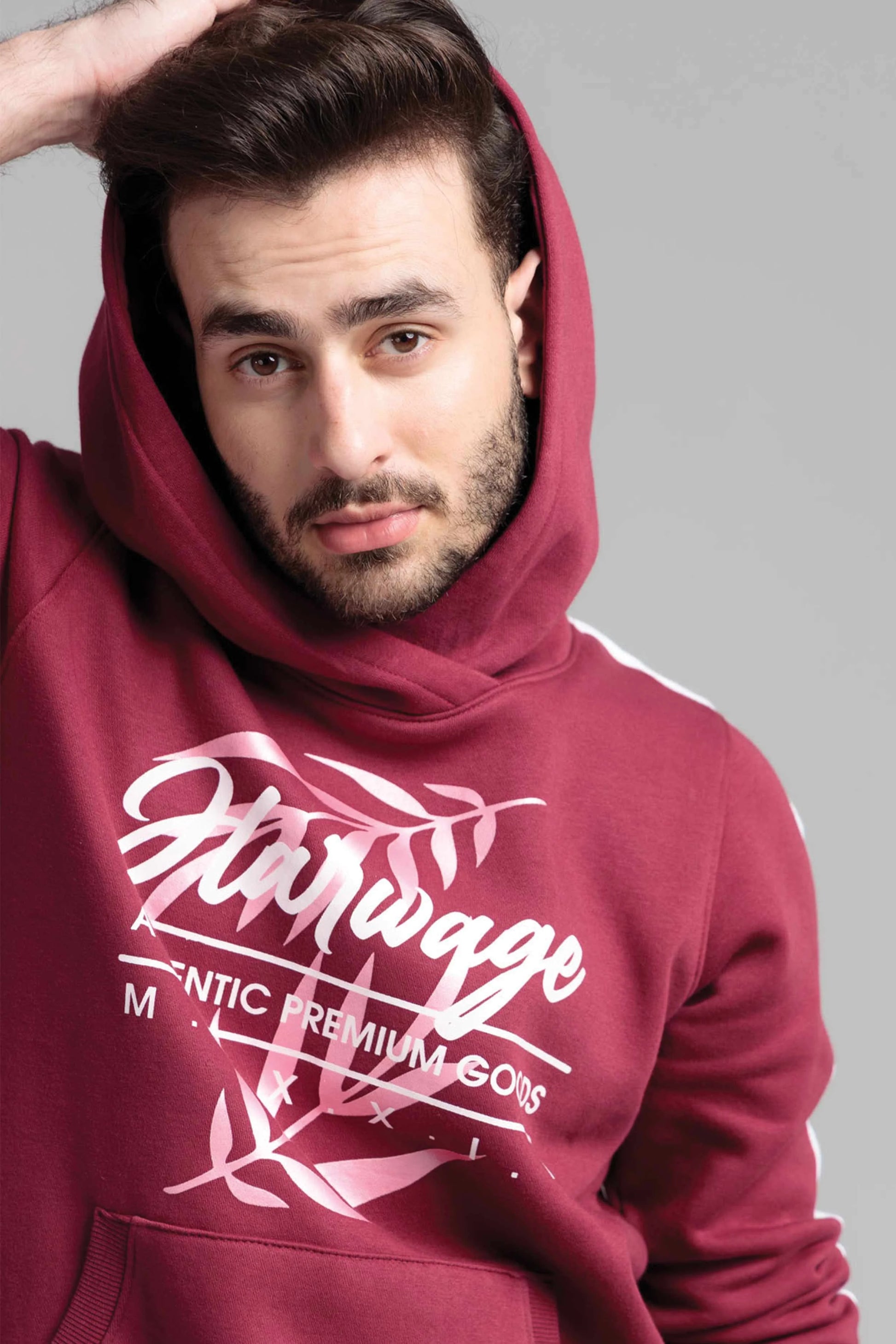 Man wearing a maroon hoodie with white text and design on a gray background