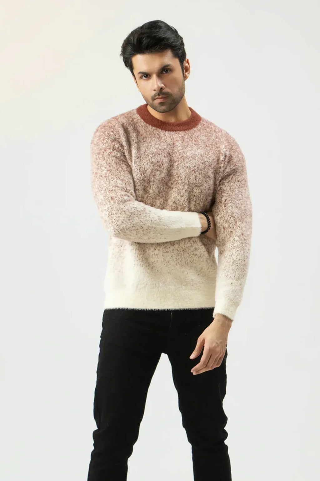 Man wearing a patterned sweater and black pants on a white 
background
