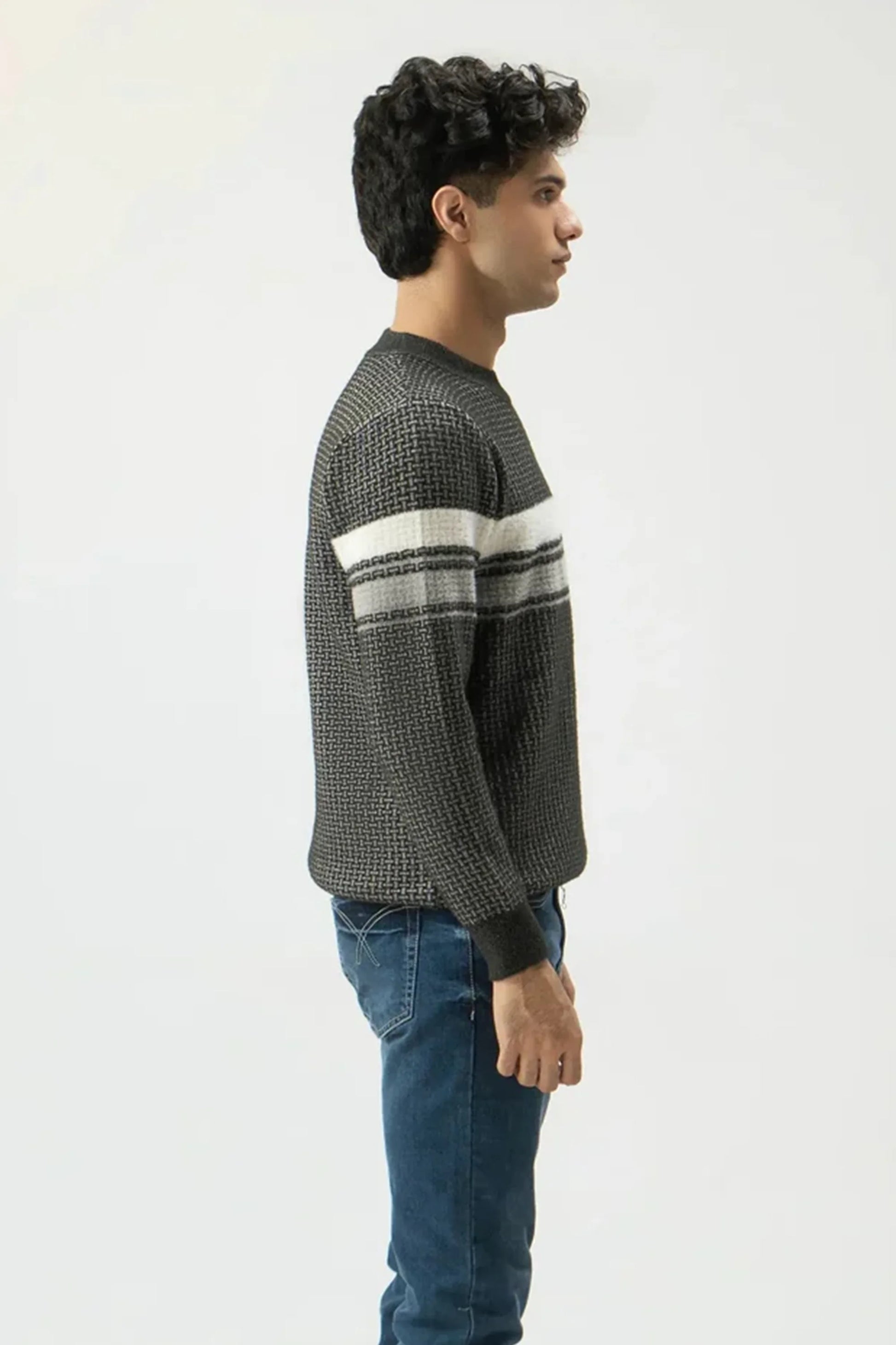 Man wearing a patterned sweater and jeans on a white background