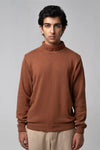 Man wearing a turtleneck sweater in brown against a gray background