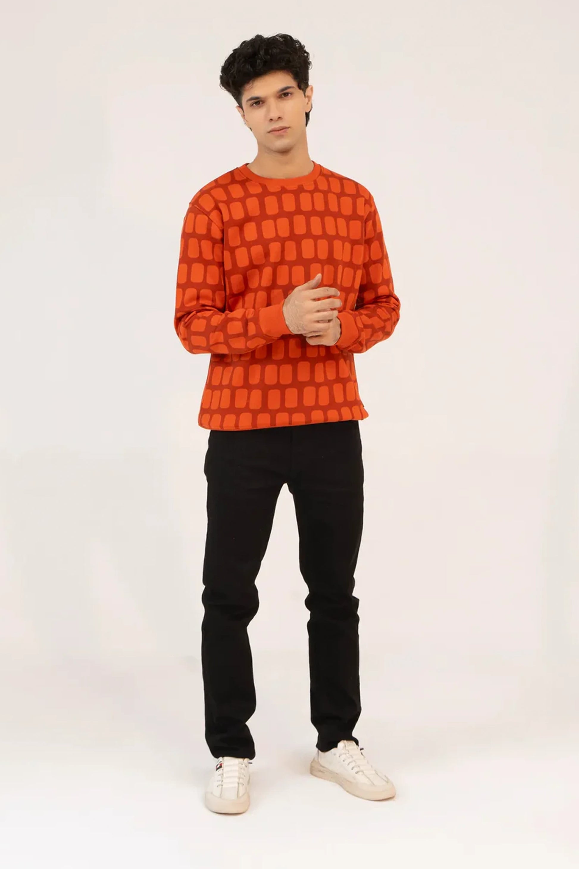 Men wearing Men Red Geometric Sweatshirt styled with black pants in studio