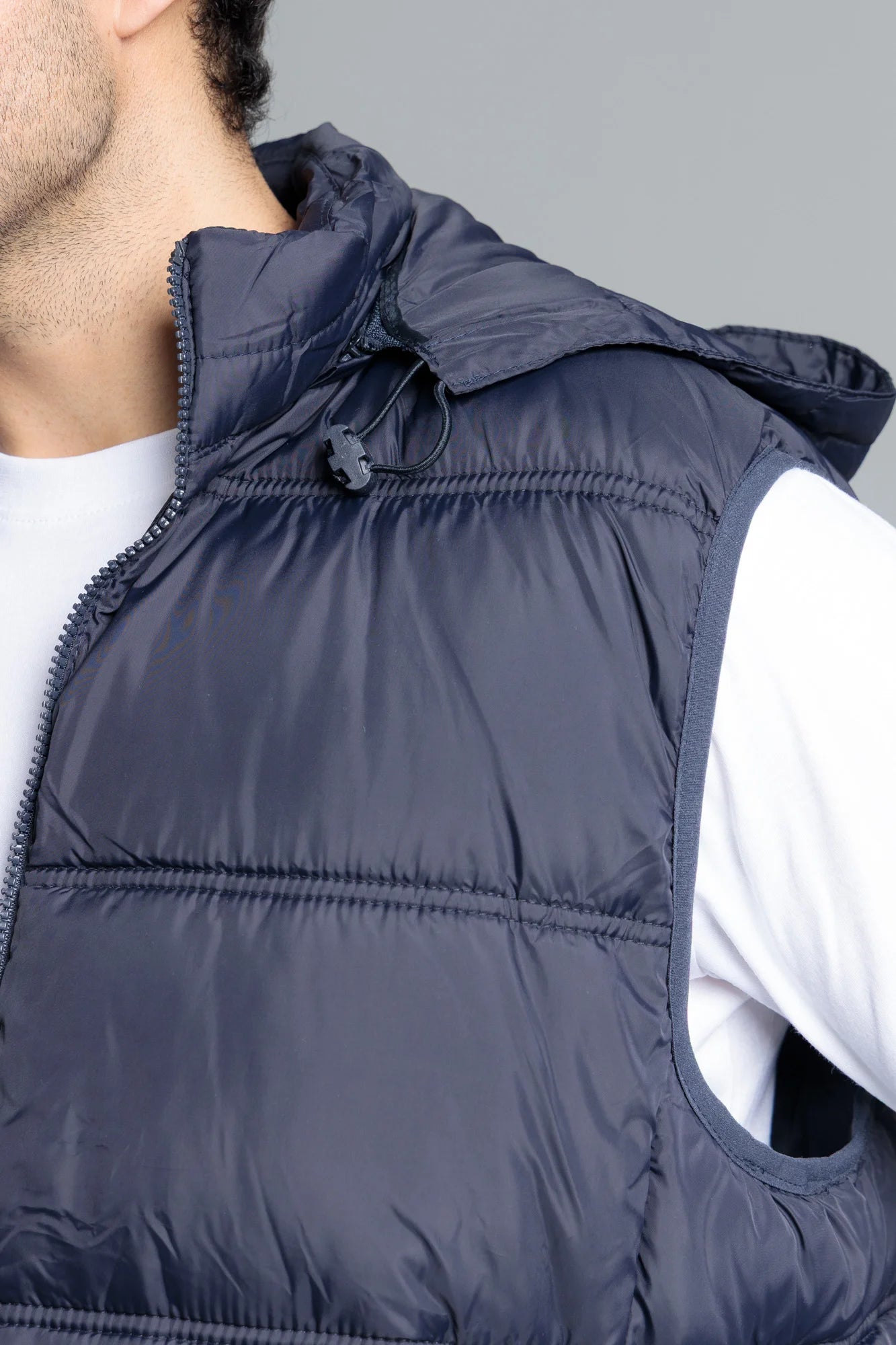 Navy blue puffer vest worn by a person on a gray background